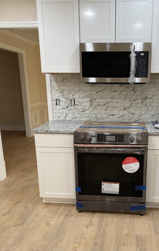 208 Woodland Dr, Summerville, SC 29485 - kitchen featuring ornamental molding, white cabinetry, light stone countertops, and stainless steel appliances