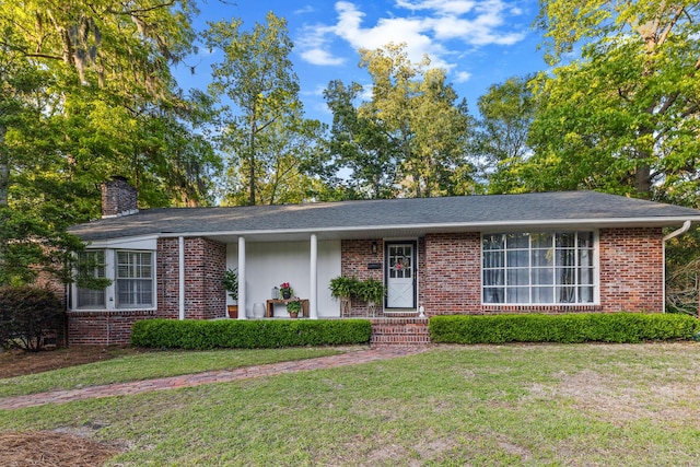 ranch-style house with a chimney, a front yard, and brick siding