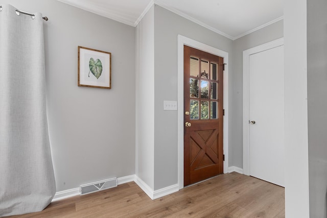foyer featuring light wood finished floors, visible vents, baseboards, and crown molding