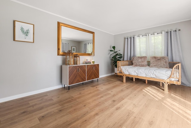 sitting room with light wood-type flooring, baseboards, and ornamental molding