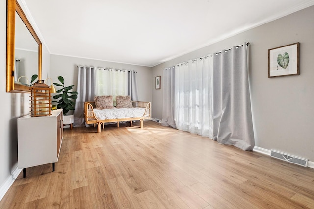 sitting room with baseboards, light wood-type flooring, crown molding, and visible vents