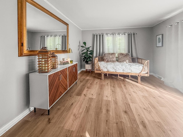 living area featuring light wood-type flooring, baseboards, and crown molding