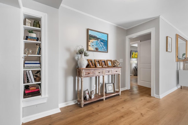 corridor featuring light wood-style floors, baseboards, and crown molding