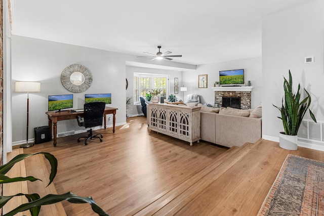living room with baseboards, a fireplace, light wood-style flooring, a ceiling fan, and visible vents