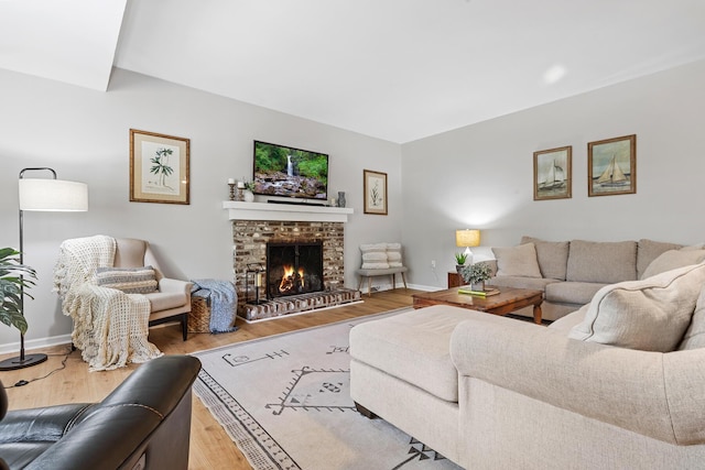 living area featuring a fireplace, light wood-style floors, and baseboards