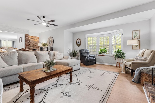 living area with light wood-style floors, ceiling fan, and baseboards