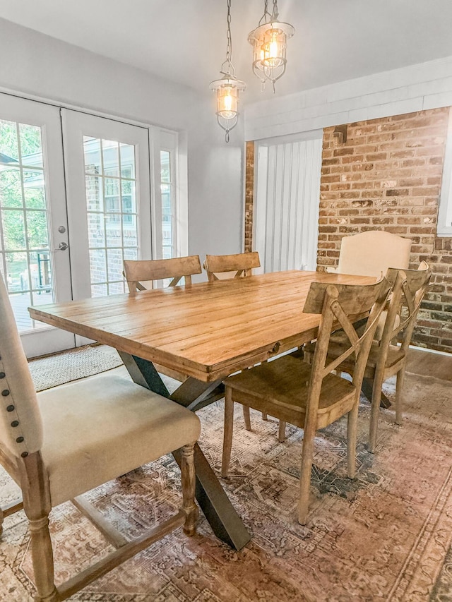 dining space featuring brick wall and french doors