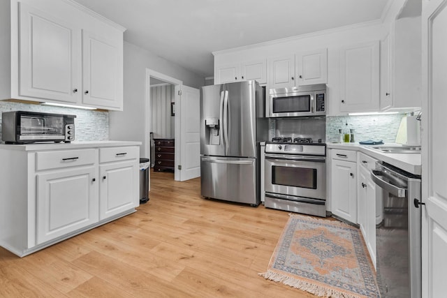 kitchen with light countertops, decorative backsplash, white cabinetry, and appliances with stainless steel finishes
