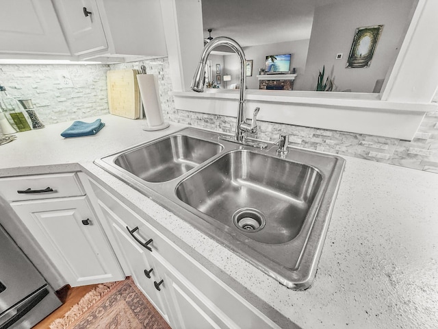 details featuring light countertops, backsplash, a sink, and white cabinetry