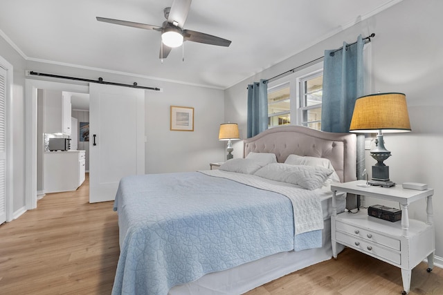 bedroom featuring light wood-style flooring, crown molding, and a barn door