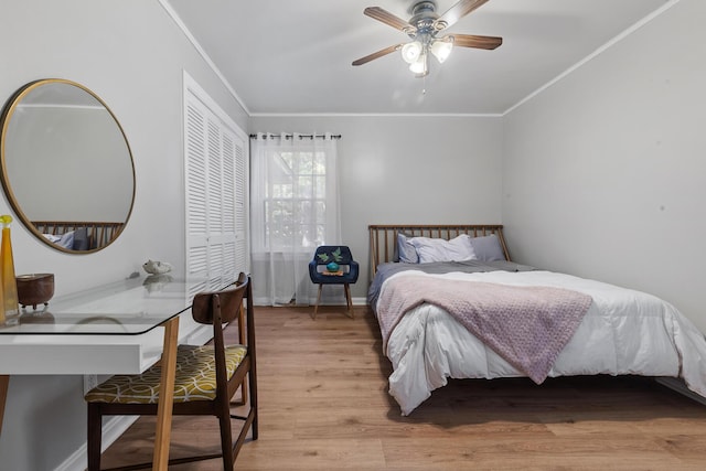 bedroom with a closet, baseboards, ornamental molding, ceiling fan, and light wood finished floors