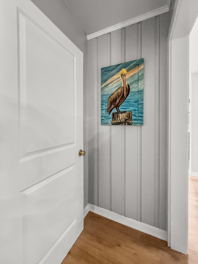 interior details featuring a decorative wall, baseboards, and wood finished floors