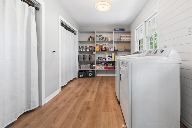 clothes washing area featuring washer and clothes dryer, light wood-style floors, and laundry area