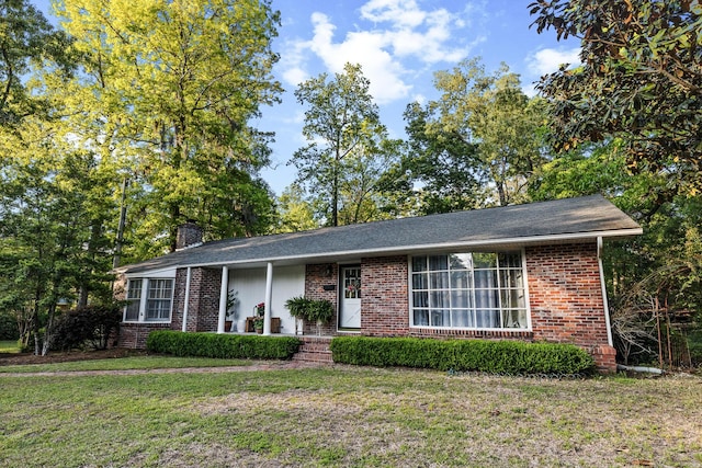 ranch-style home with a front yard, brick siding, a chimney, and a shingled roof