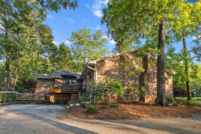 view of property exterior featuring brick siding and a wooden deck