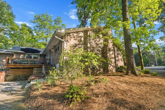 view of property exterior with brick siding, stairway, and a deck