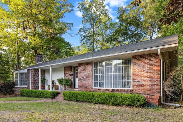 ranch-style house with brick siding, a front yard, and a chimney