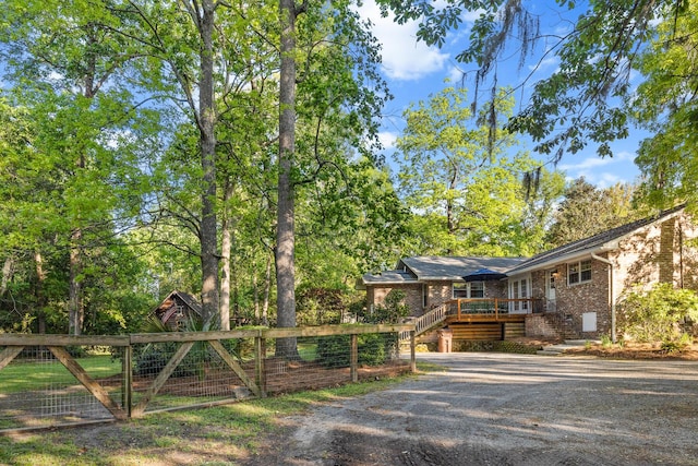 view of front of property featuring brick siding, fence, a wooden deck, and stairway