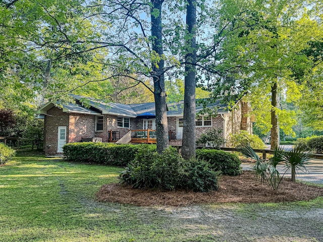 view of front of home with brick siding, a deck, and a front lawn