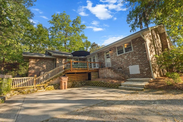 view of front facade with brick siding, stairs, and a deck