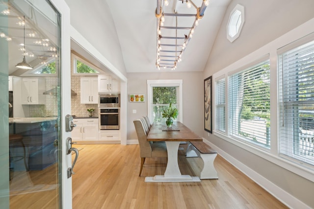 dining room with a chandelier, lofted ceiling, and light wood-type flooring