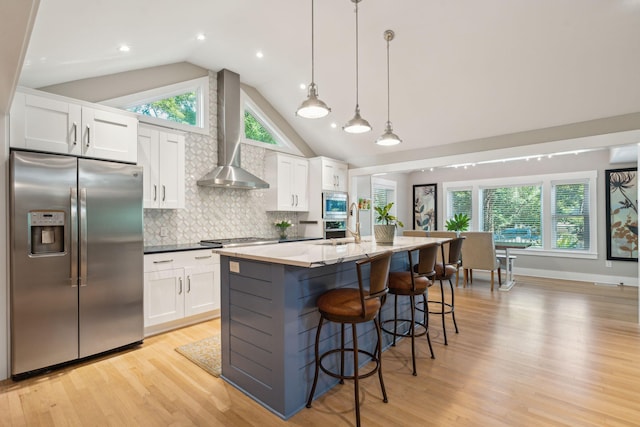 kitchen with white cabinets, wall chimney exhaust hood, and stainless steel appliances