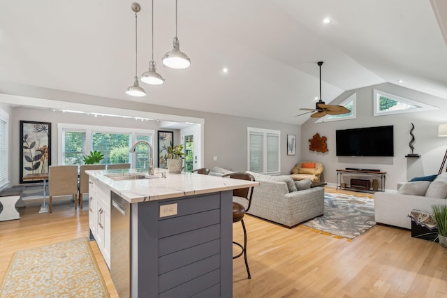 kitchen featuring pendant lighting, sink, an island with sink, white cabinetry, and a breakfast bar area