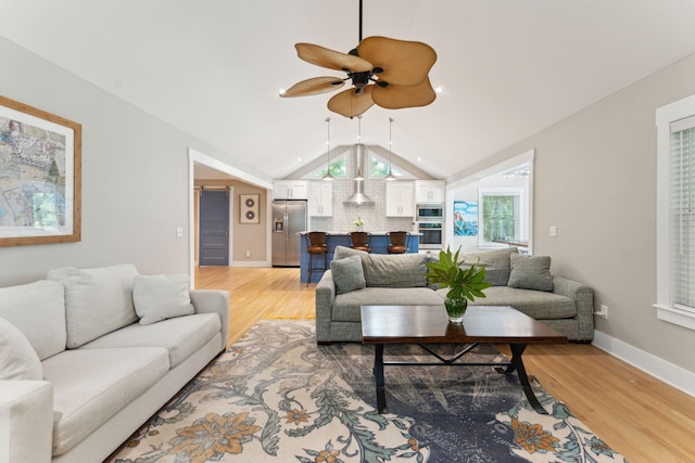 living room with light hardwood / wood-style floors, ceiling fan, and lofted ceiling