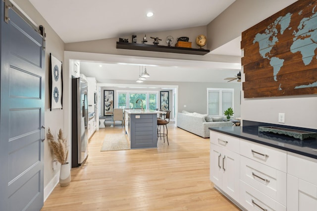 kitchen with pendant lighting, a breakfast bar, white cabinets, a barn door, and stainless steel fridge with ice dispenser