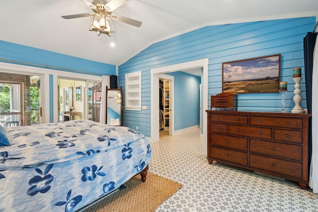 bedroom featuring lofted ceiling, wooden walls, ceiling fan, access to exterior, and a spacious closet