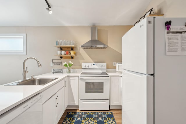 kitchen with white appliances, sink, wall chimney range hood, white cabinets, and light hardwood / wood-style floors