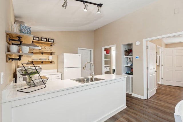 kitchen featuring sink, vaulted ceiling, dark hardwood / wood-style floors, built in features, and white fridge