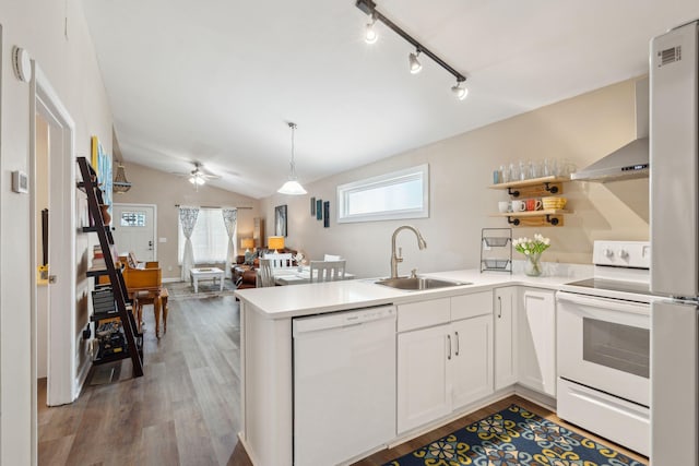 kitchen featuring kitchen peninsula, white appliances, sink, hardwood / wood-style flooring, and white cabinets