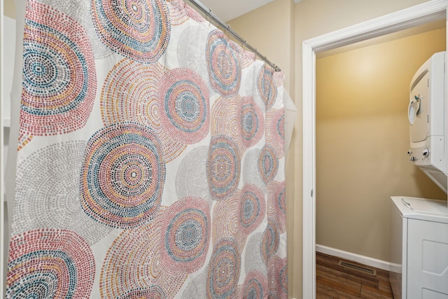 bathroom featuring stacked washer and clothes dryer and hardwood / wood-style flooring