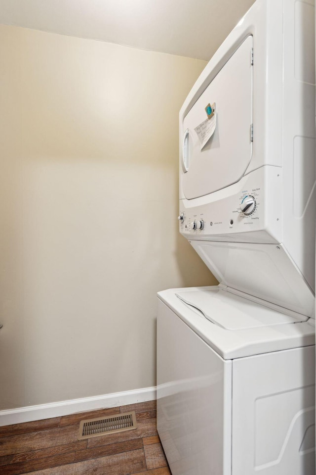 clothes washing area with stacked washer and dryer and dark wood-type flooring