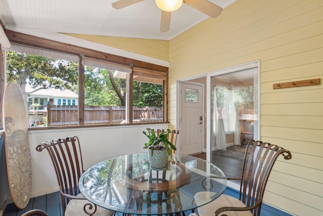 dining area featuring wood-type flooring, wooden walls, ceiling fan, and lofted ceiling