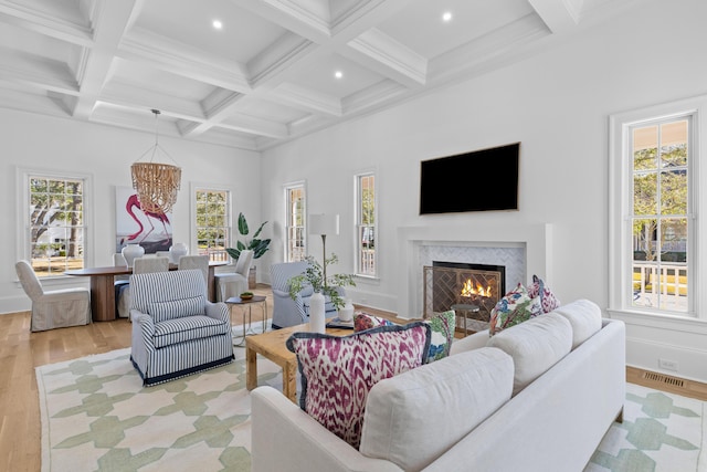 living area featuring beam ceiling, visible vents, a premium fireplace, light wood-style floors, and coffered ceiling