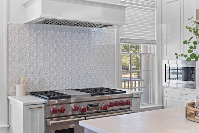 kitchen with stainless steel appliances, light countertops, custom range hood, and white cabinetry