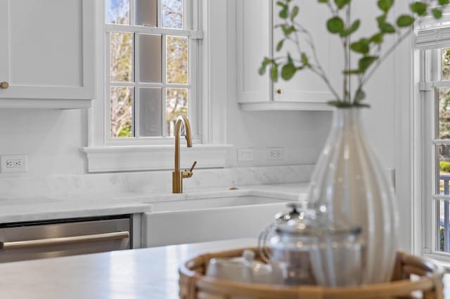 kitchen with dishwasher, white cabinetry, light countertops, and a sink