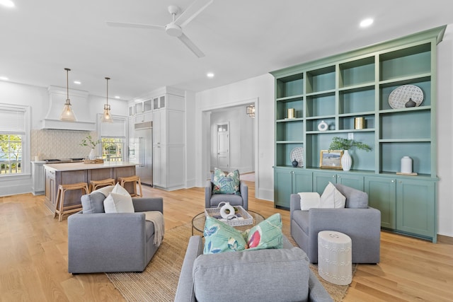 living room with light wood-style floors, a ceiling fan, and recessed lighting