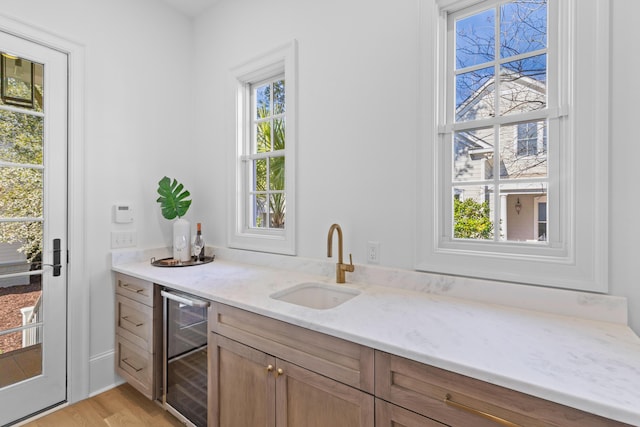 bar featuring light wood finished floors, wine cooler, and a sink