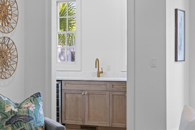 bar featuring beverage cooler, visible vents, and a sink