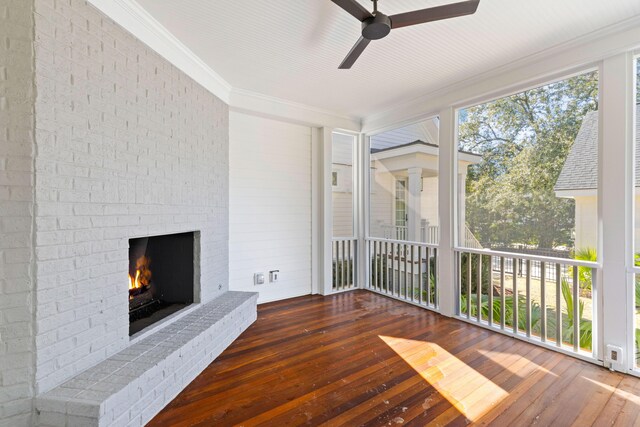 interior space featuring ornamental molding, a fireplace, ceiling fan, and wood finished floors