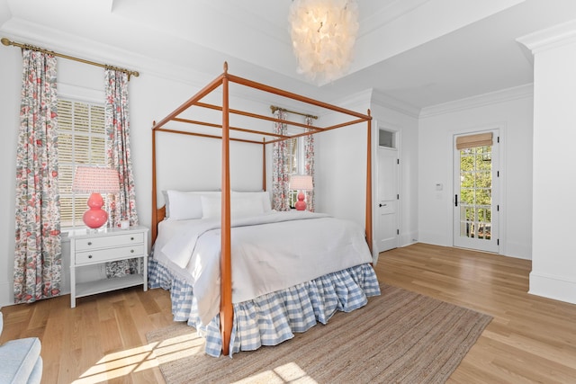 bedroom featuring a chandelier, ornamental molding, and light wood-style floors