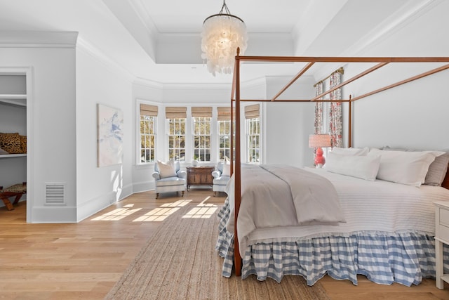 bedroom with light wood finished floors, baseboards, visible vents, crown molding, and a chandelier