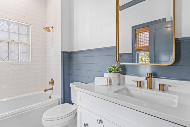 bathroom with toilet, wainscoting, shower / bathing tub combination, and vanity