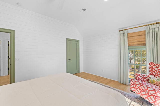 bedroom with vaulted ceiling, wood finished floors, and visible vents