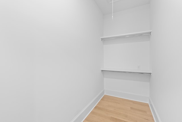 walk in closet with attic access and wood finished floors