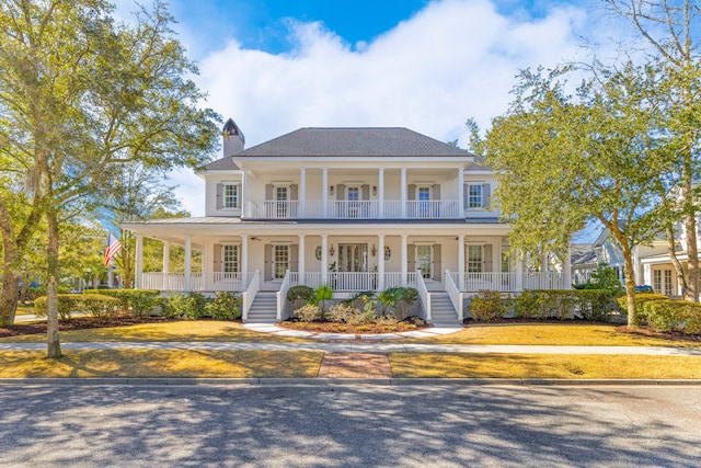 view of front of property featuring a balcony, covered porch, and a chimney