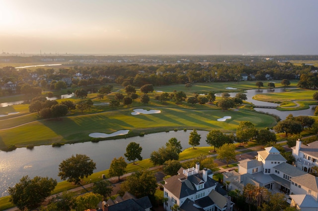 aerial view at dusk featuring a residential view, a water view, and golf course view